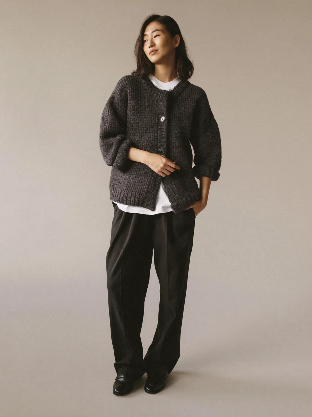 Woman in a charcoal chunky-knit cardigan over a white T-shirt