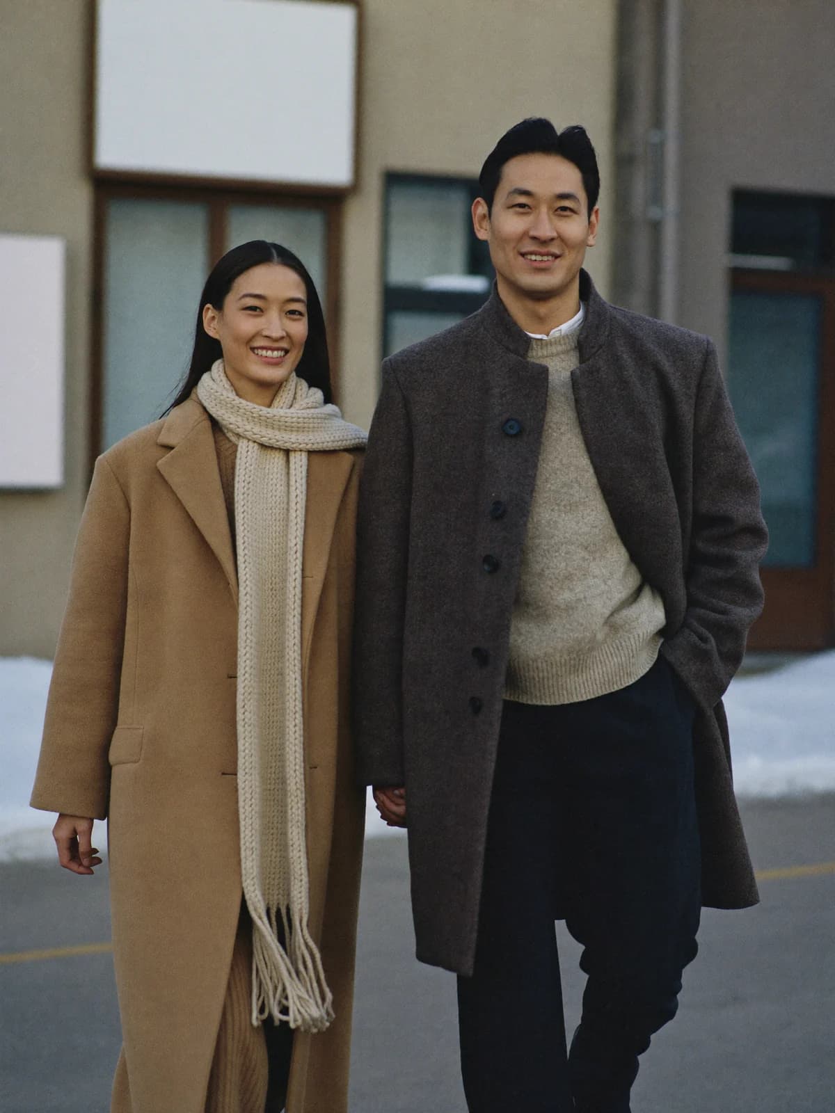 Couple in winter coats, she wears a cream knit scarf