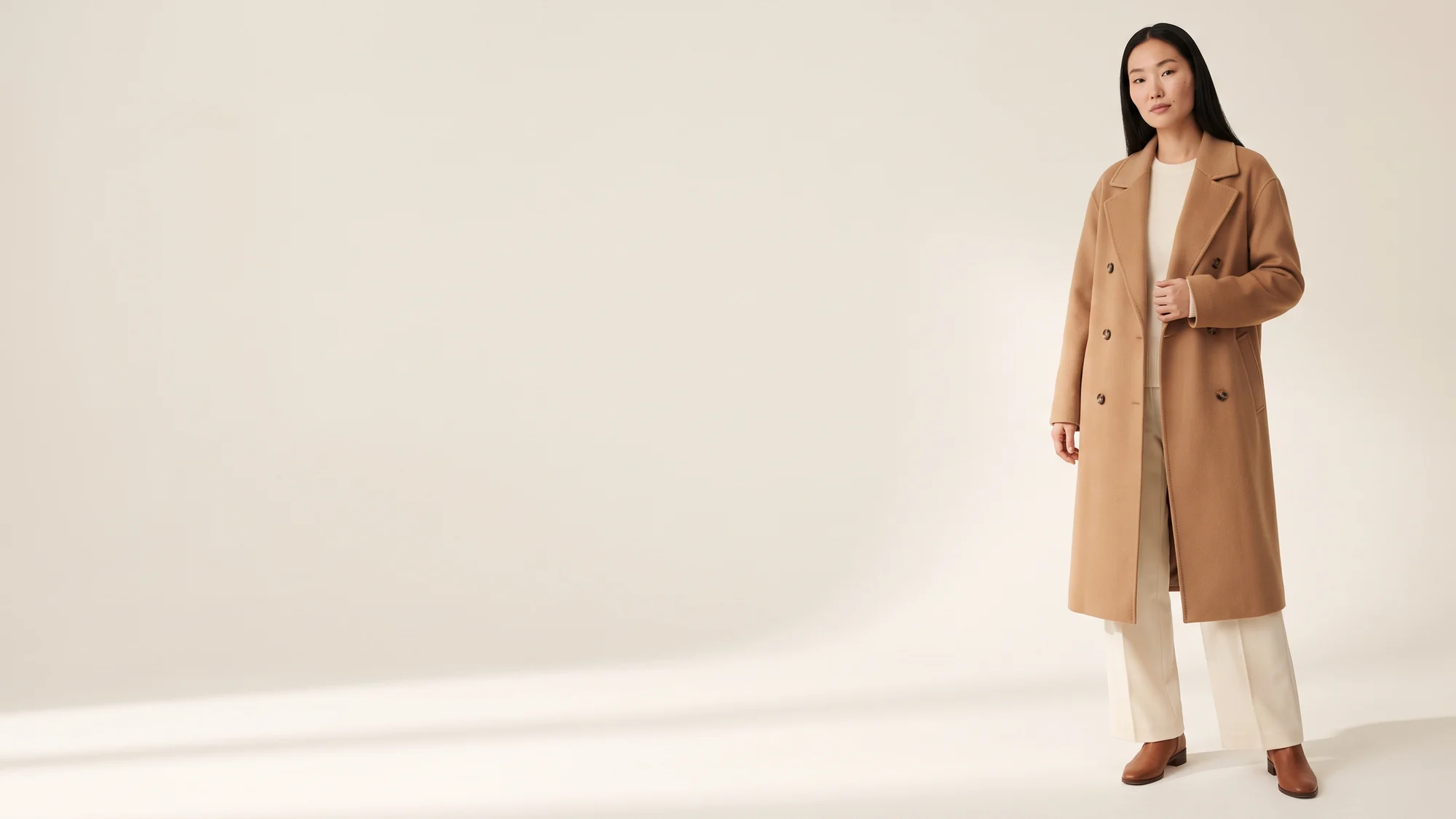 Woman in a camel double-breasted wool coat and ivory trousers