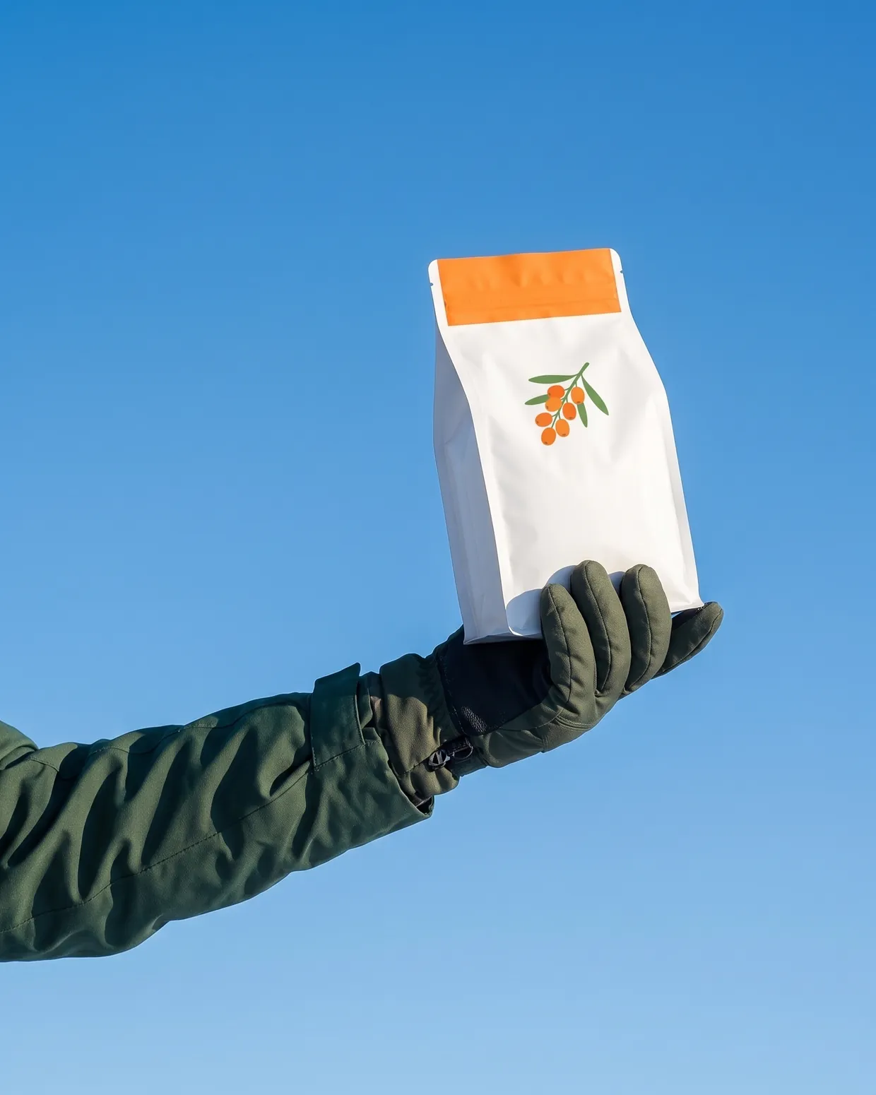 A gloved hand holding the pouch up against a winter-blue sky